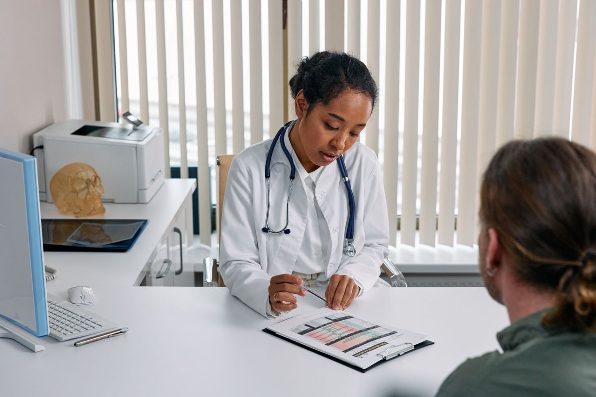 A doctor sitting across from a patient explaining results, the human part of care that AI should protect, not replace
