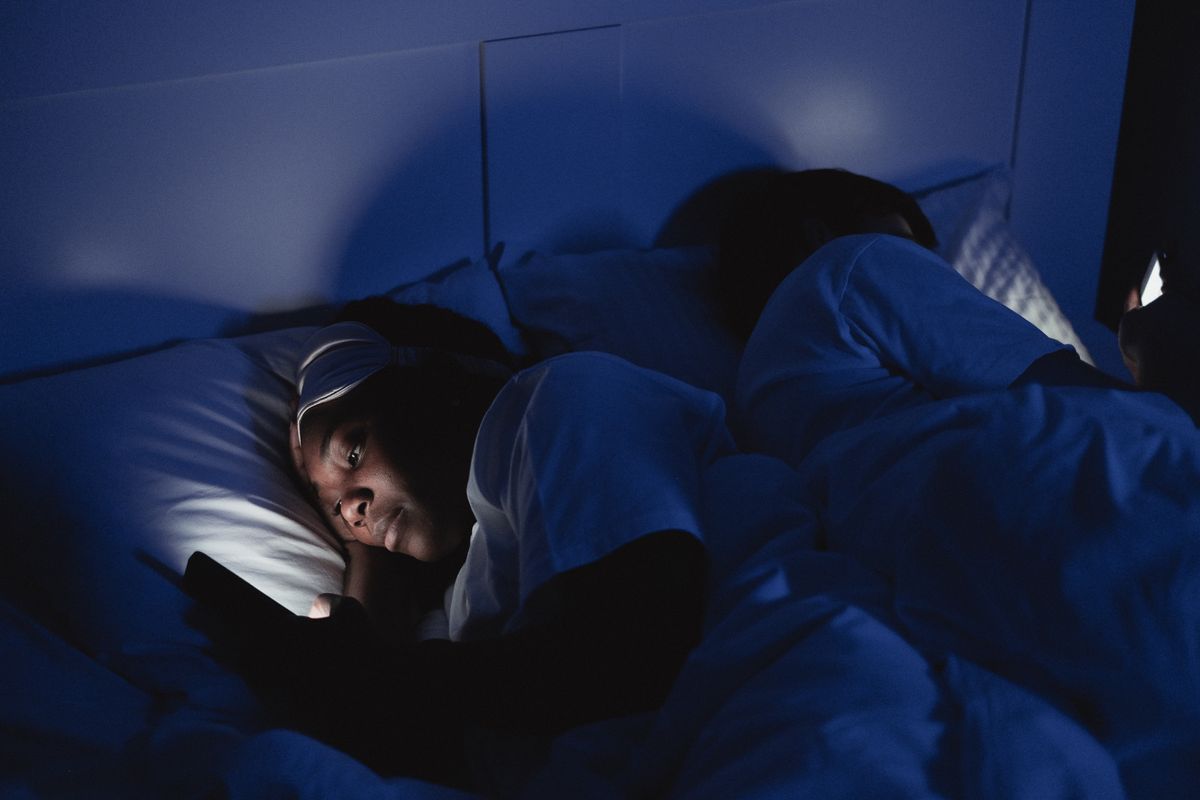 A woman lying in bed at night typing into a chatbot on her phone for mental health support