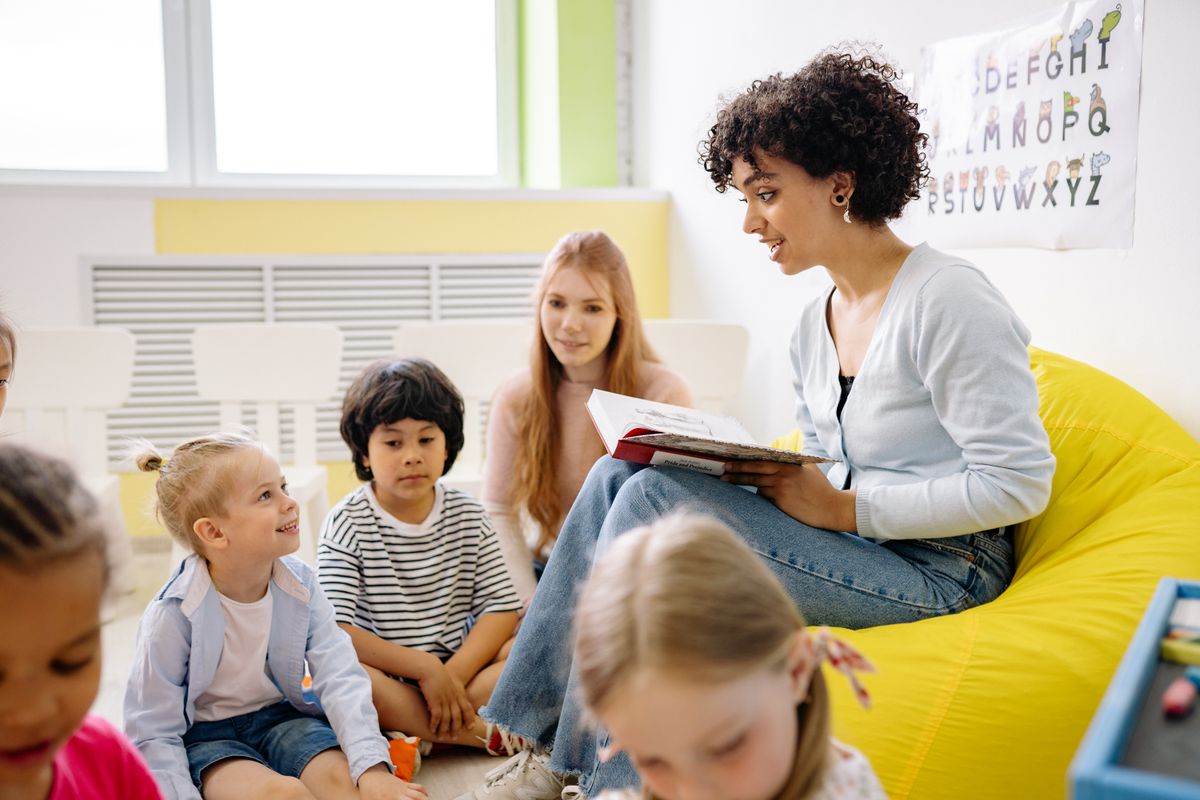 A teacher reading to young children in a classroom during the back to school season, when parents rush to book physicals and checkups