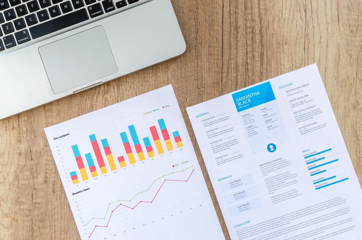 Charts and performance data on a desk next to a laptop, used to decide the best time to run medical practice Google Ads