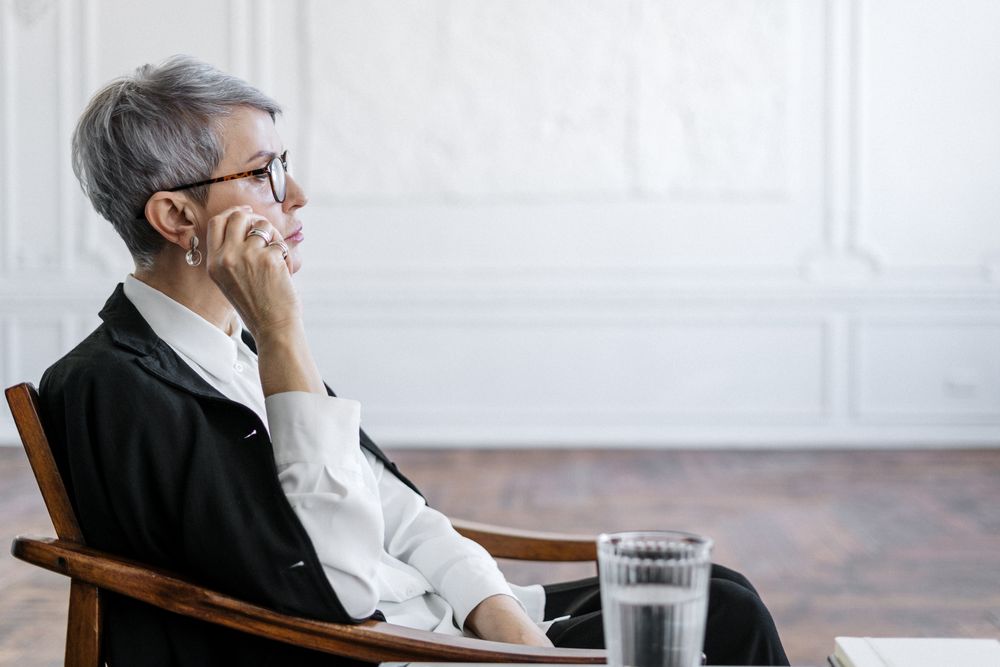 An older patient sitting in a chair making a phone call to book a medical appointment because online booking is not offered to existing patients