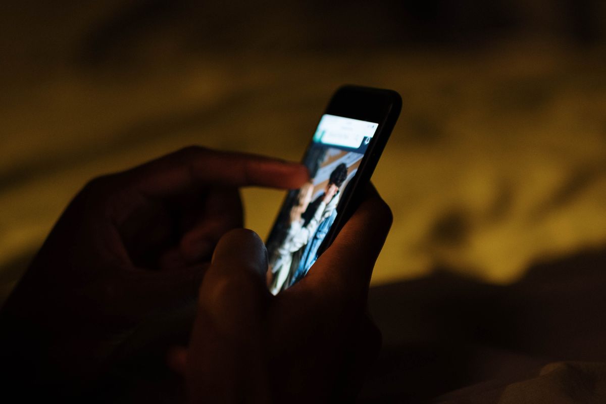 A person on their phone at night asking an AI assistant to recommend a doctor, the moment a practice is either named or skipped