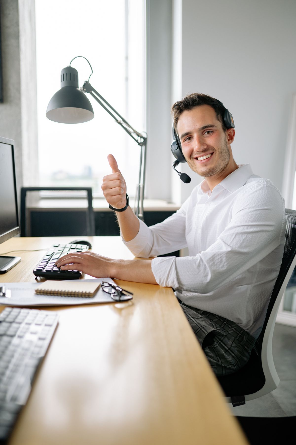 A smiling front desk staffer wearing a headset at a medical practice, the place where AI actually helps a practice book more patients