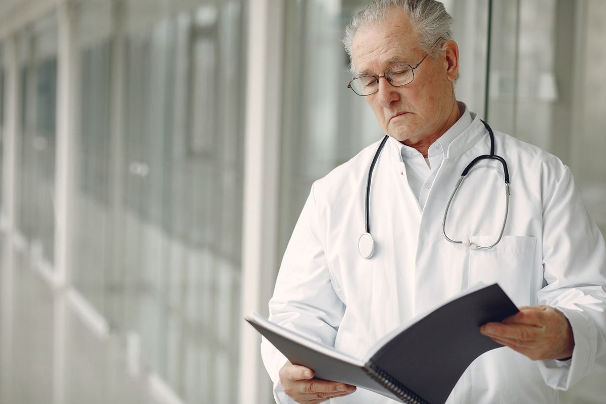 A physician reviewing a folder of notes, the way a plastic surgeon might study a new AI patient acquisition course