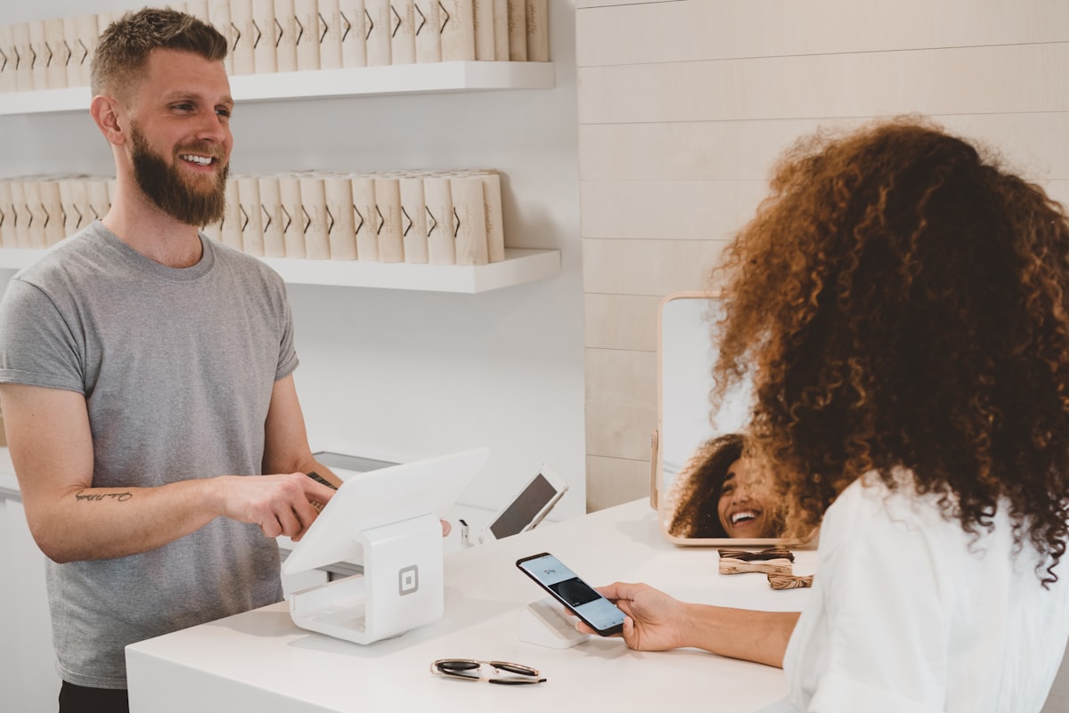 A smiling staff member welcoming a visitor at a bright front desk during a medical practice grand opening event