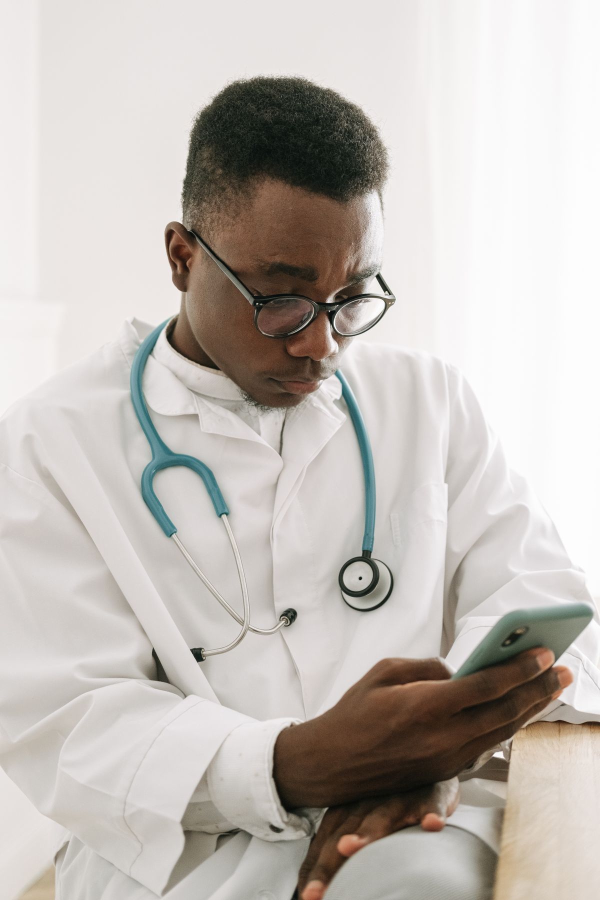 A doctor in a white coat reading and responding to patient reviews on his phone