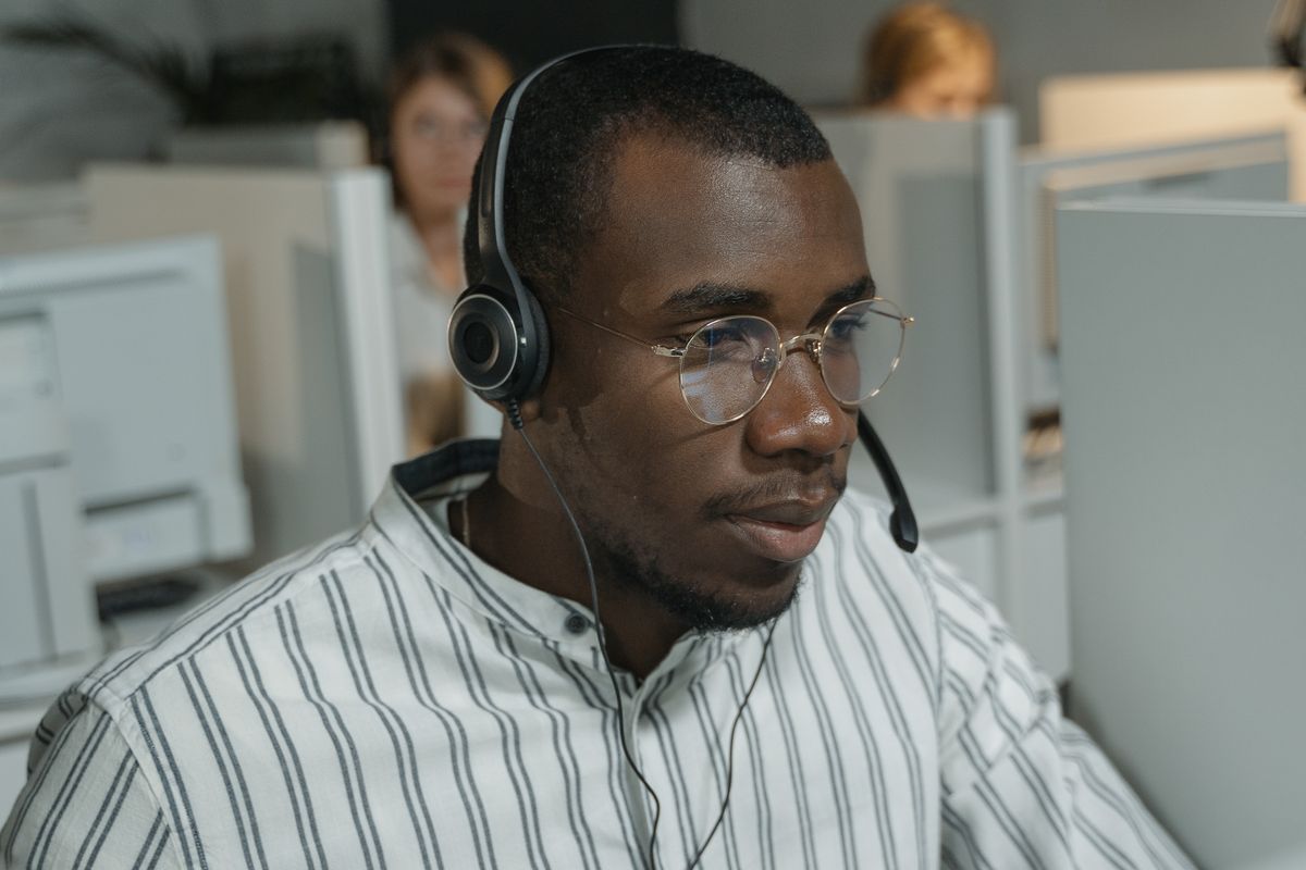 A friendly front desk agent wearing a headset answering patient phone calls in a medical office