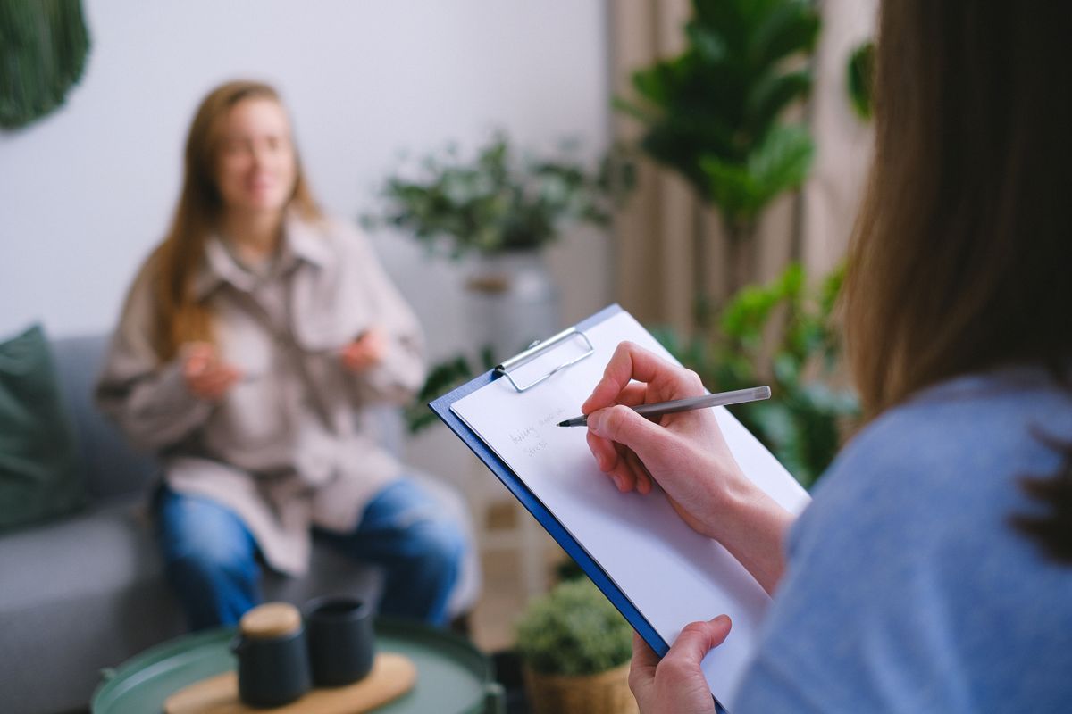 A female provider sits with a patient during a consultation, the kind of comfort that shapes whether a patient books and returns