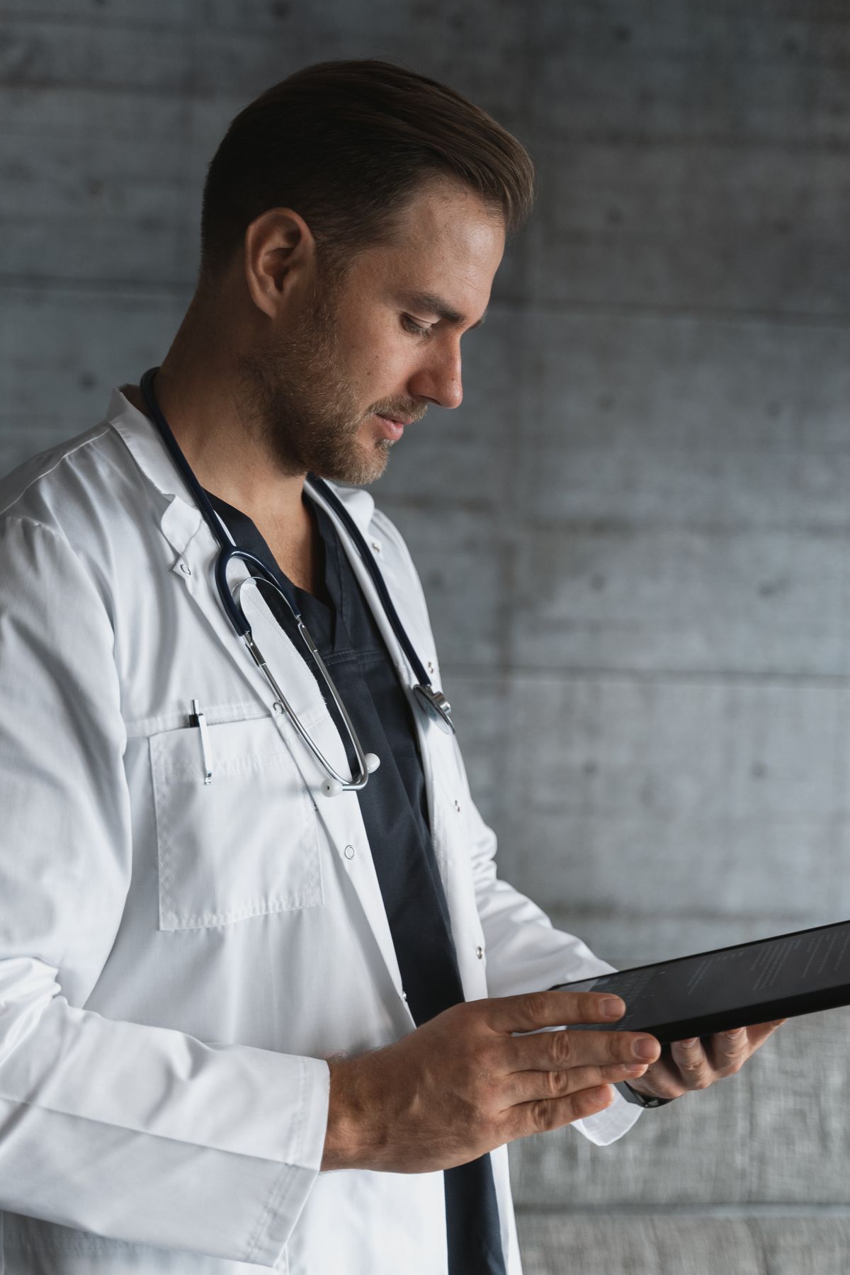 A doctor reviewing patient notes on a tablet, the kind of documentation an ambient AI scribe now writes automatically during the visit