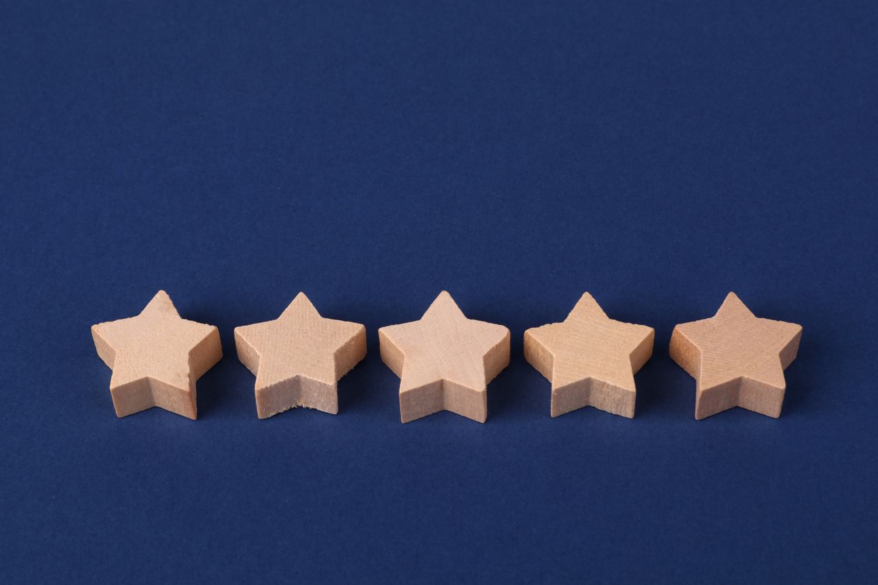 Five wooden stars on a blue background, representing how a medical practice star rating affects its Google Ads cost per patient