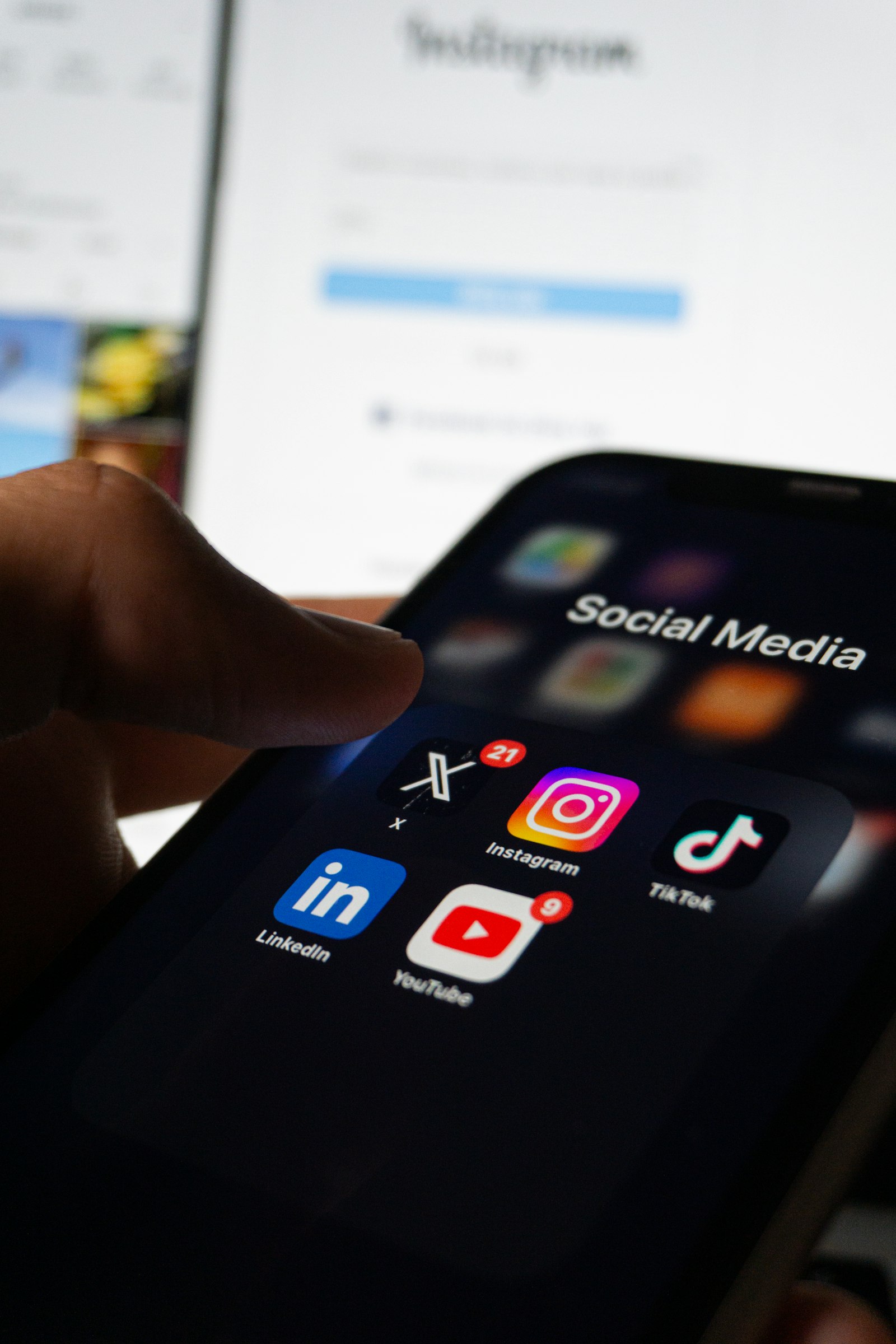 A hand holding a phone showing social media apps, representing a medical practice checking its follower count