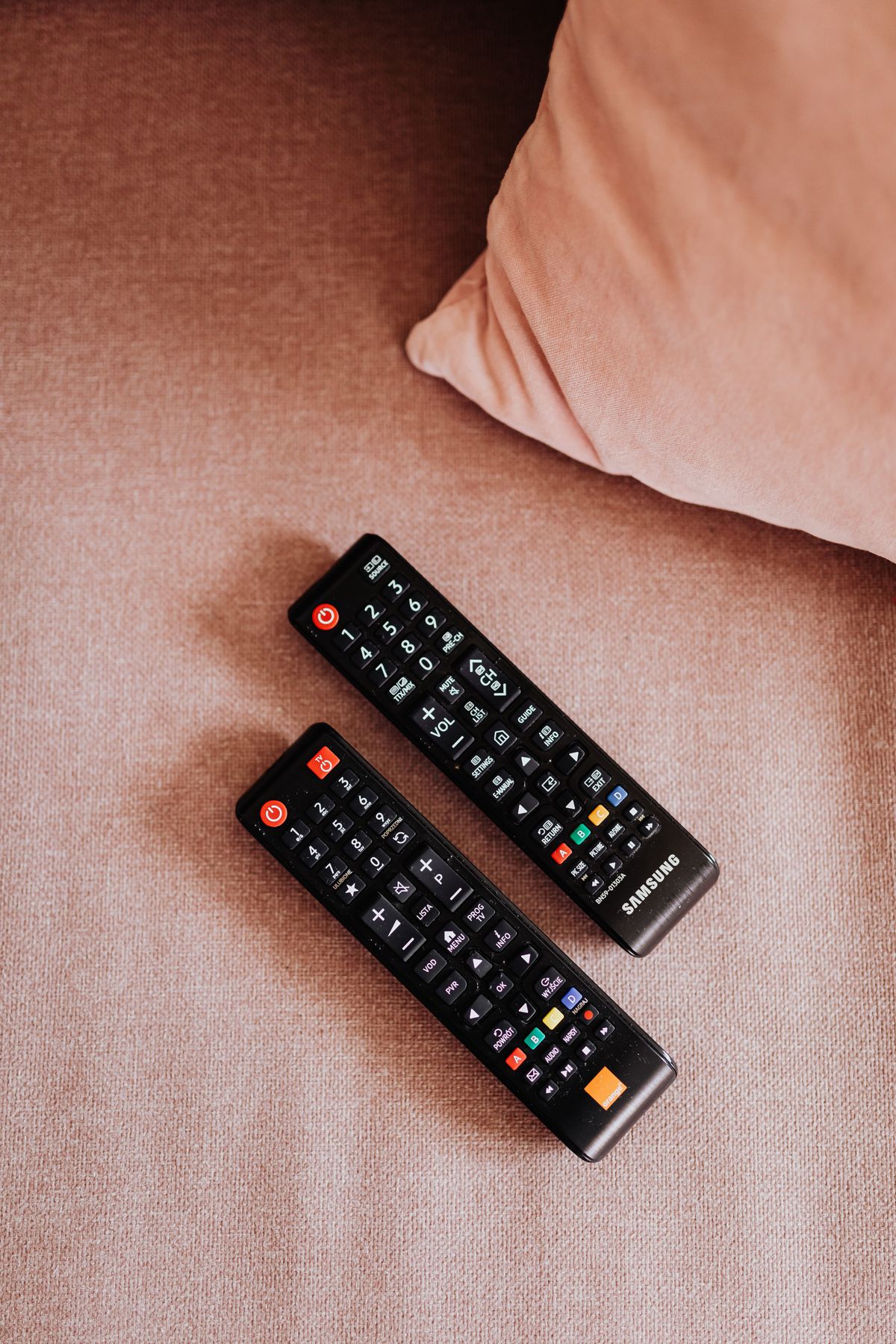 TV remote controls on a couch, the everyday setting where patients watch streaming services that now carry connected TV ads