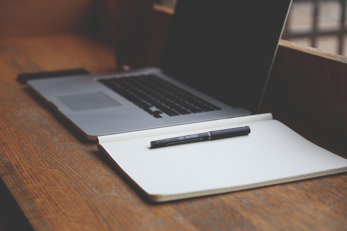 An open laptop and a blank notebook on a wooden desk, the setup for auditing your own medical practice website for trust signals
