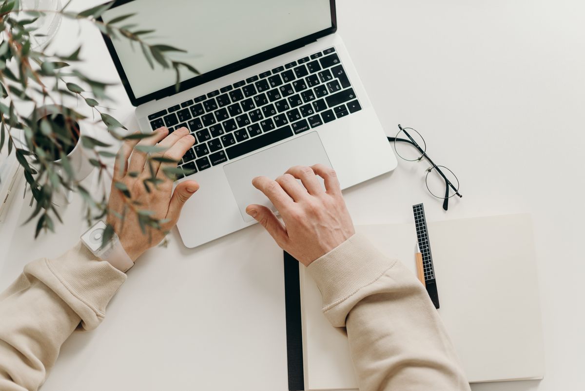Hands typing on a laptop at a clean desk, sending professional email for a medical practice