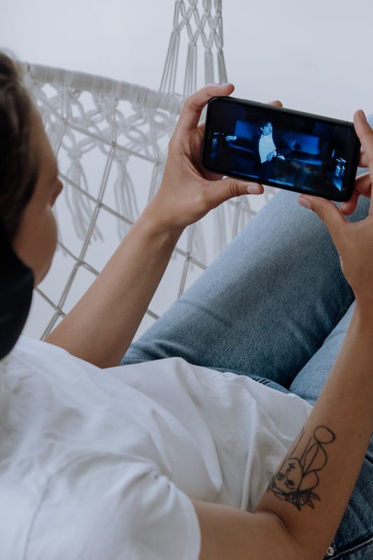 A person relaxing and watching a video on their phone, the way a patient watches a homepage video on a medical practice website