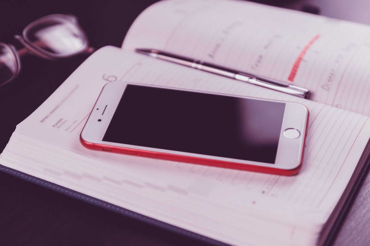 A phone resting on an open appointment planner, showing the link between an AI receptionist and a medical practice scheduling system