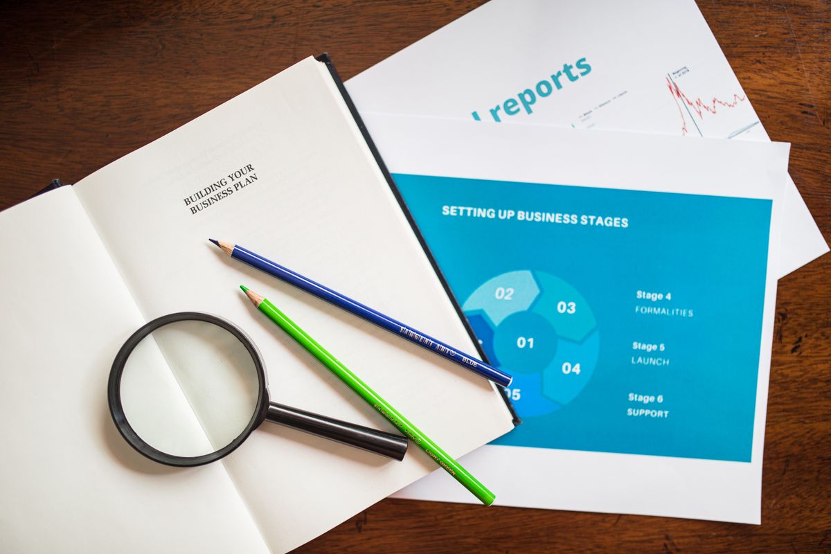 A business plan notebook, magnifying glass and a stages diagram, the way a medical practice maps its patient marketing funnel