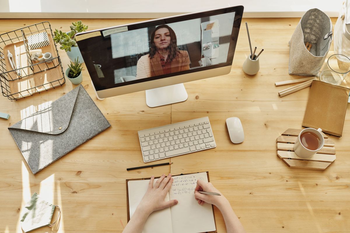 A patient watching a health video on a desktop computer and taking notes, the way people learn about a treatment before booking