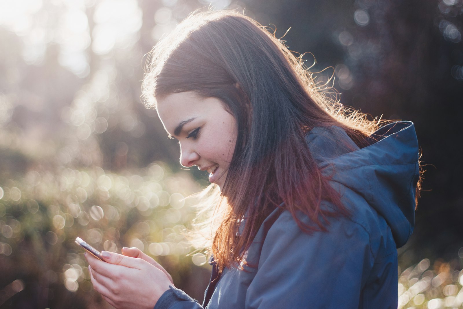 A patient smiling at her phone after seeing a booking confirmation from a medical practice