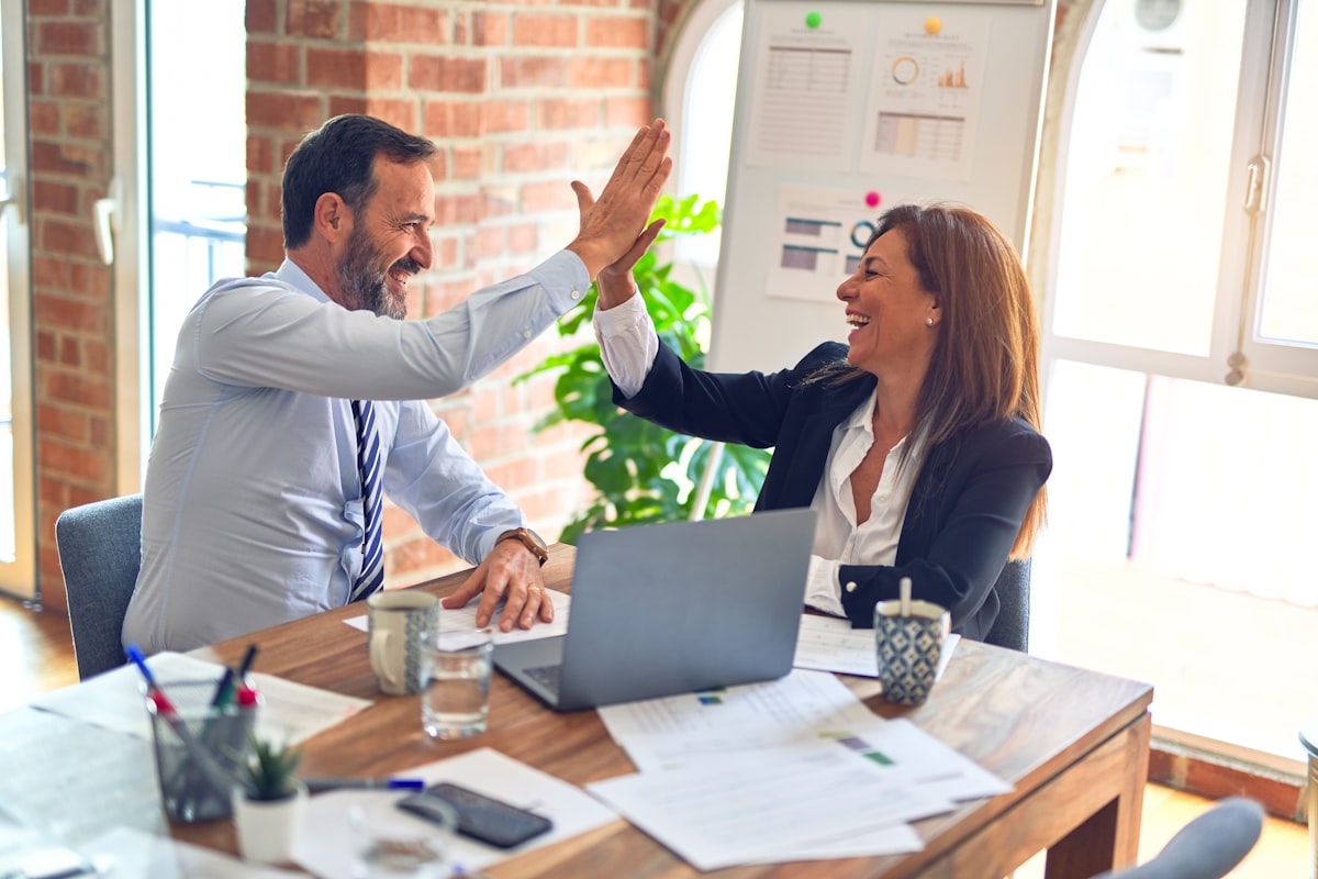 Two happy team members celebrating at a practice, the culture a strong online reputation helps you hire for