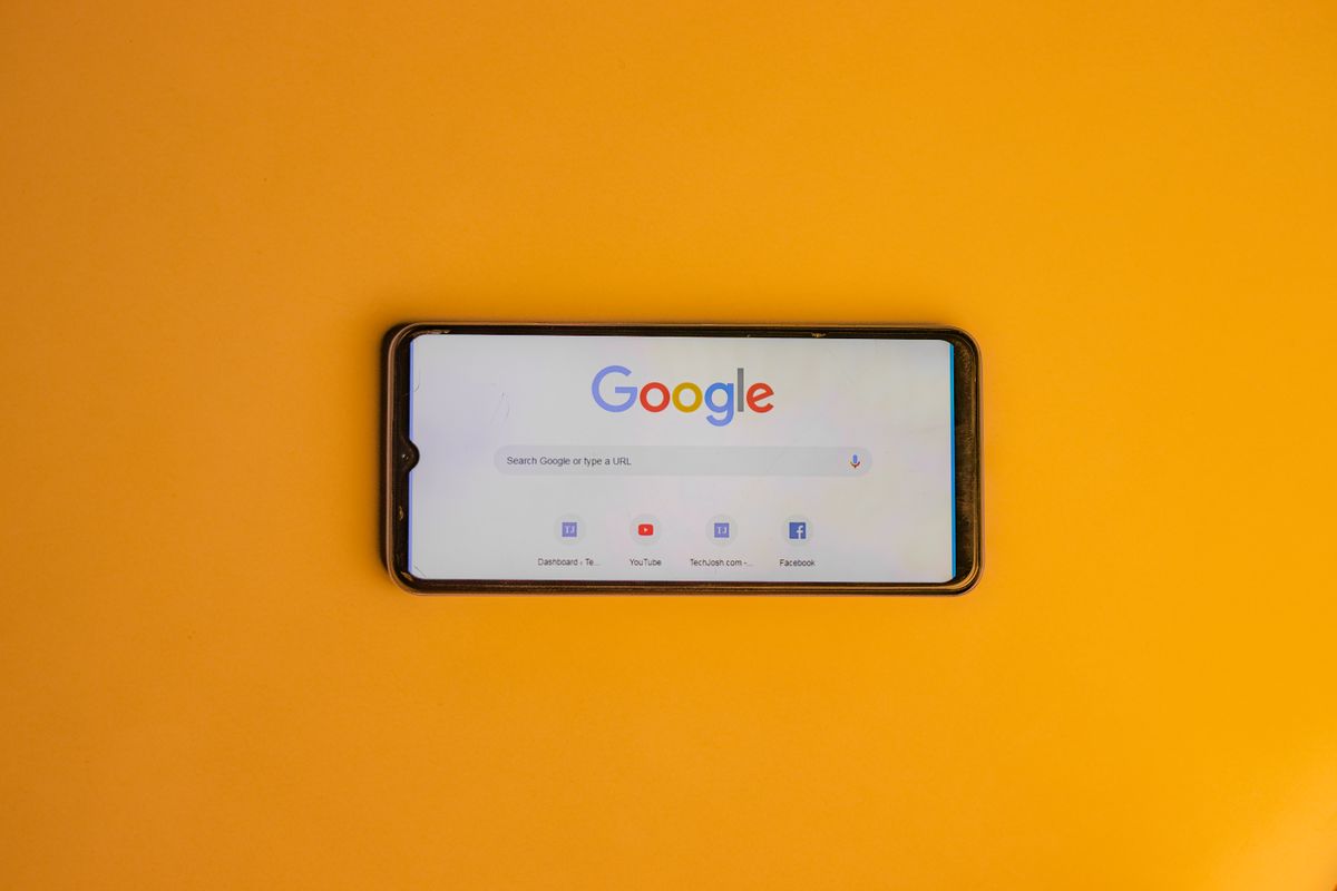 A hand holding a smartphone with a Google search page open, the way a patient looks up a medical practice before booking