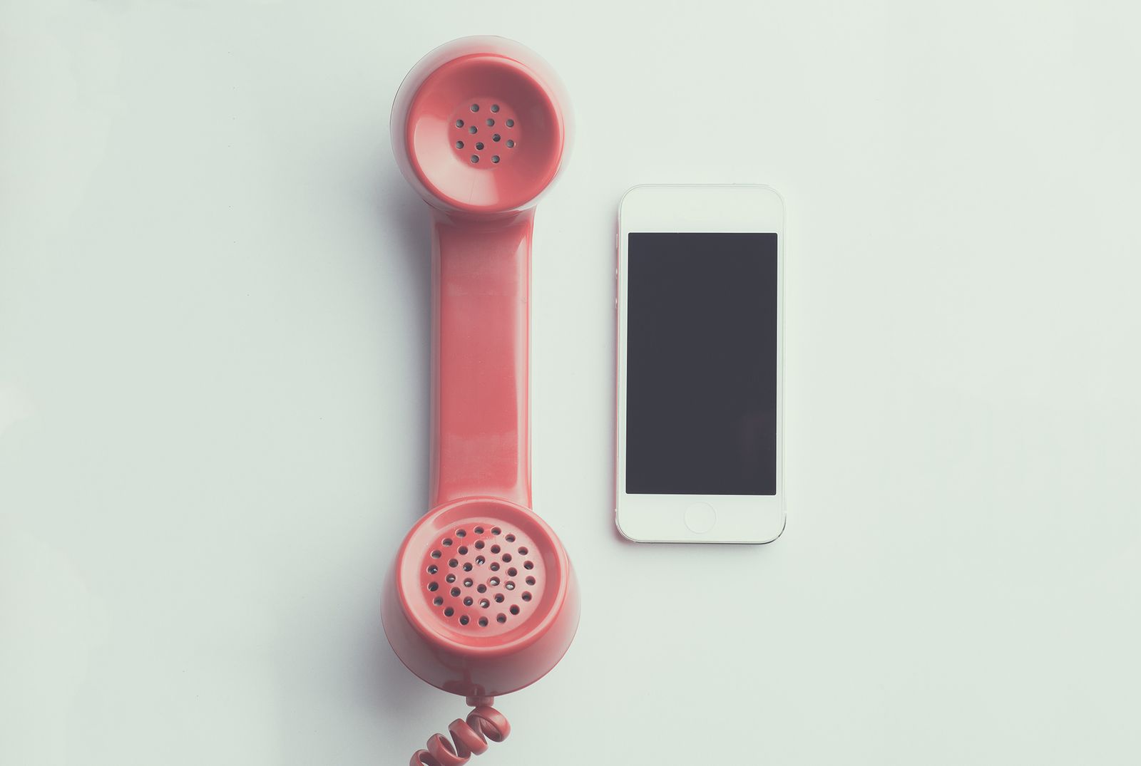 A red retro phone handset next to a smartphone, representing fake Google calls targeting a medical practice listing