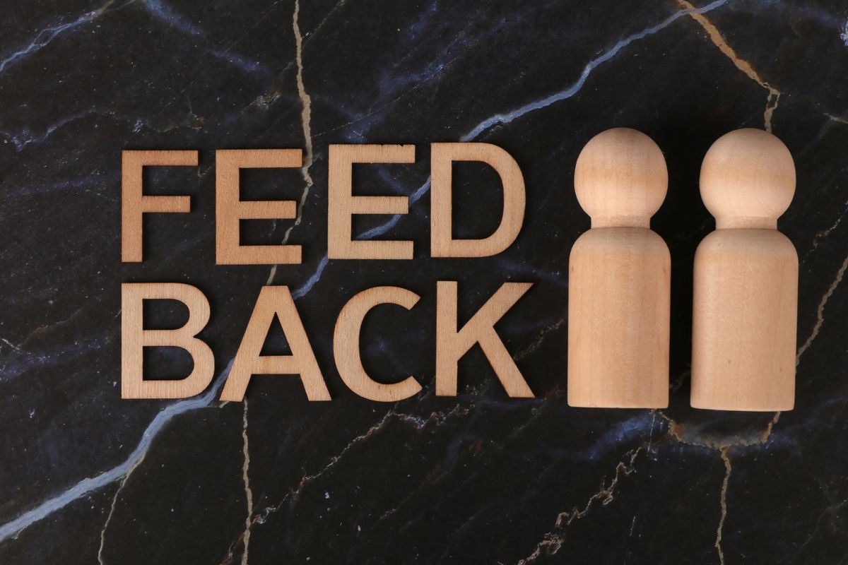 Wooden letters spelling feedback next to two figures, representing honest patient reviews under the FTC fake review rule