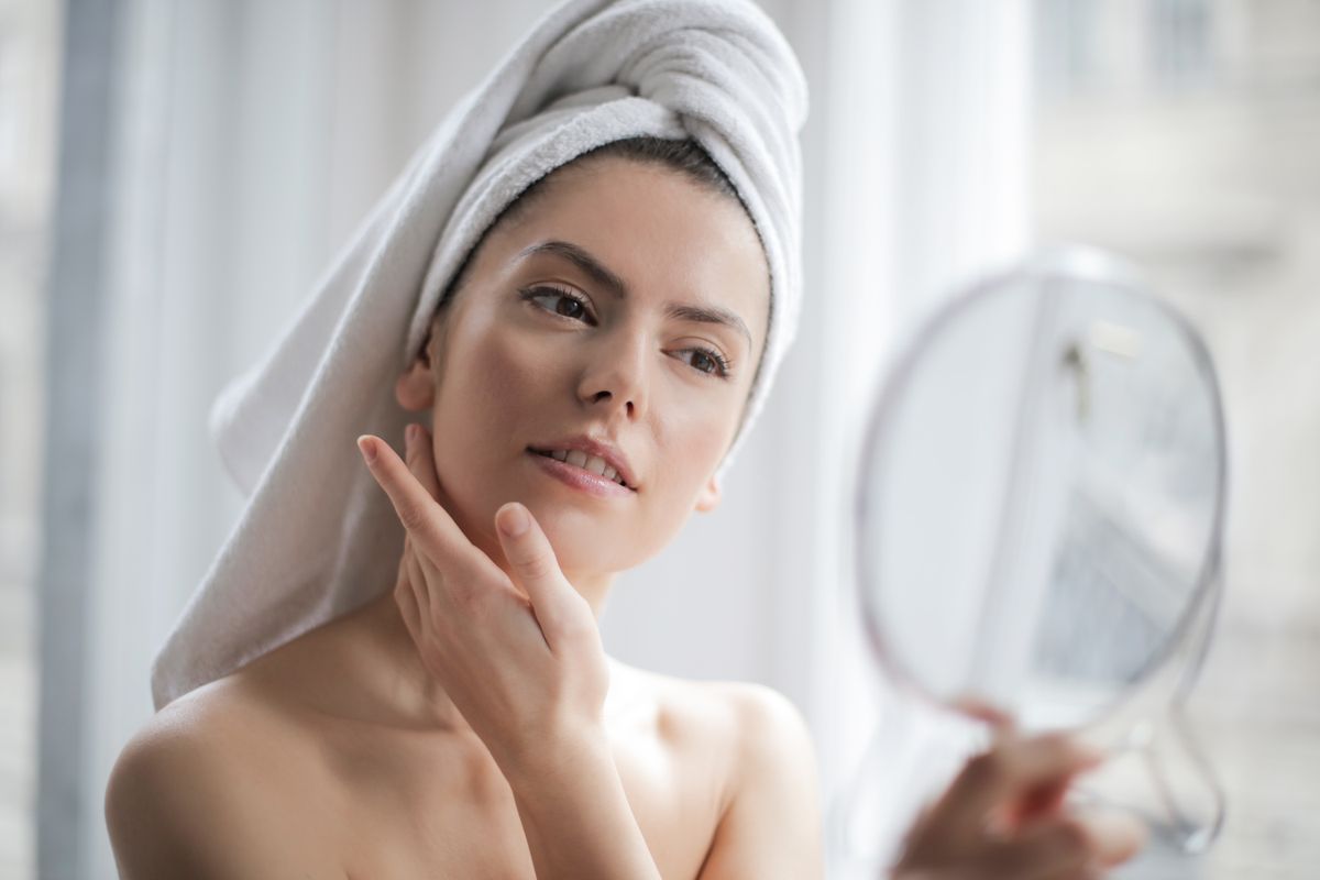Woman checking her skin in a hand mirror after a med spa facial treatment, the kind of client Google Ads and Instagram ads compete to reach