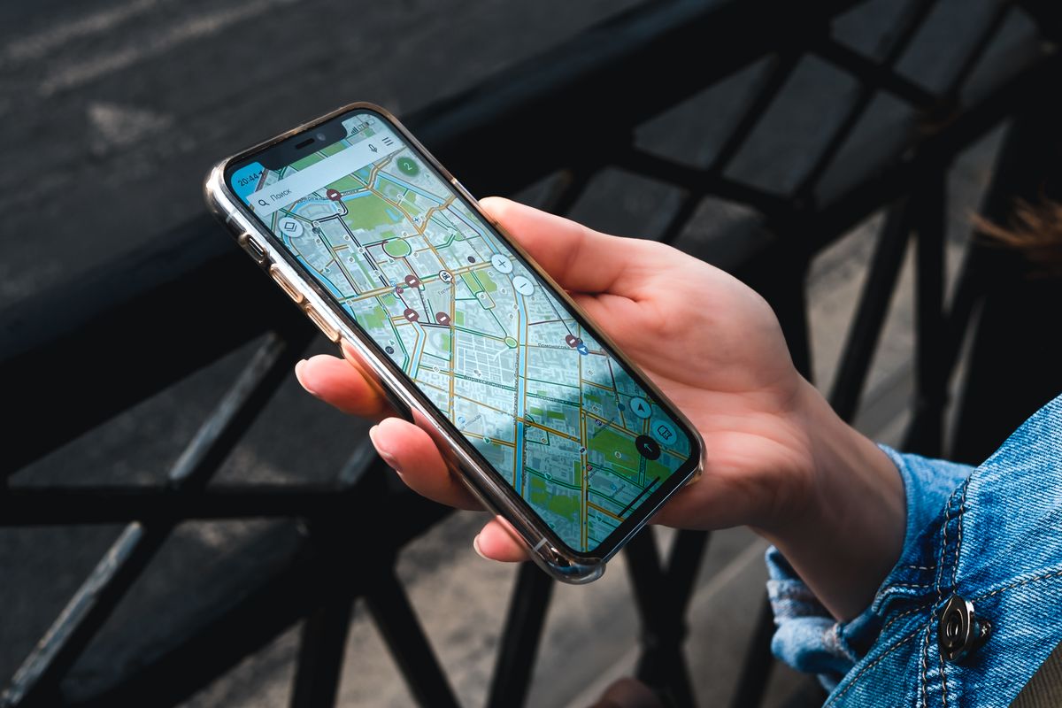 A hand holding a smartphone showing a map, how most patients first see a medical practice on Google