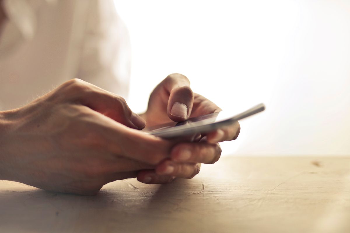 A patient typing a health question into a phone, where AI Overviews and Google search results shape which medical practice they pick