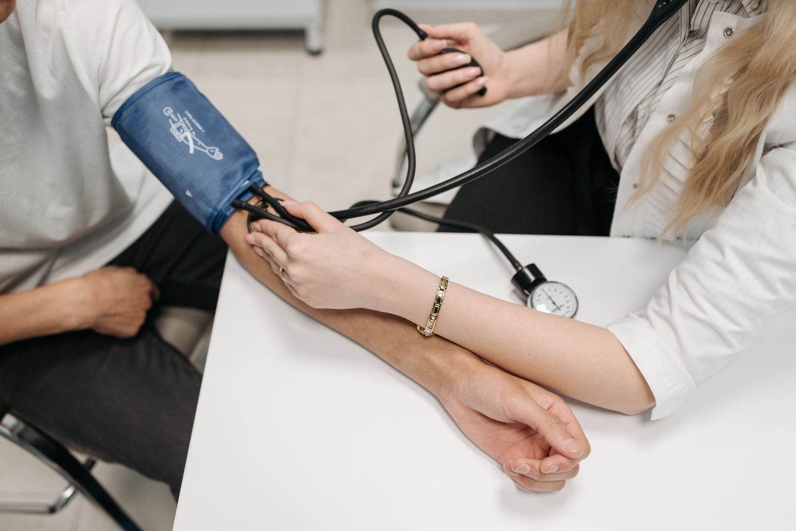 A clinician checks a patient's blood pressure by hand, the human care that patients trust more than faceless healthcare AI