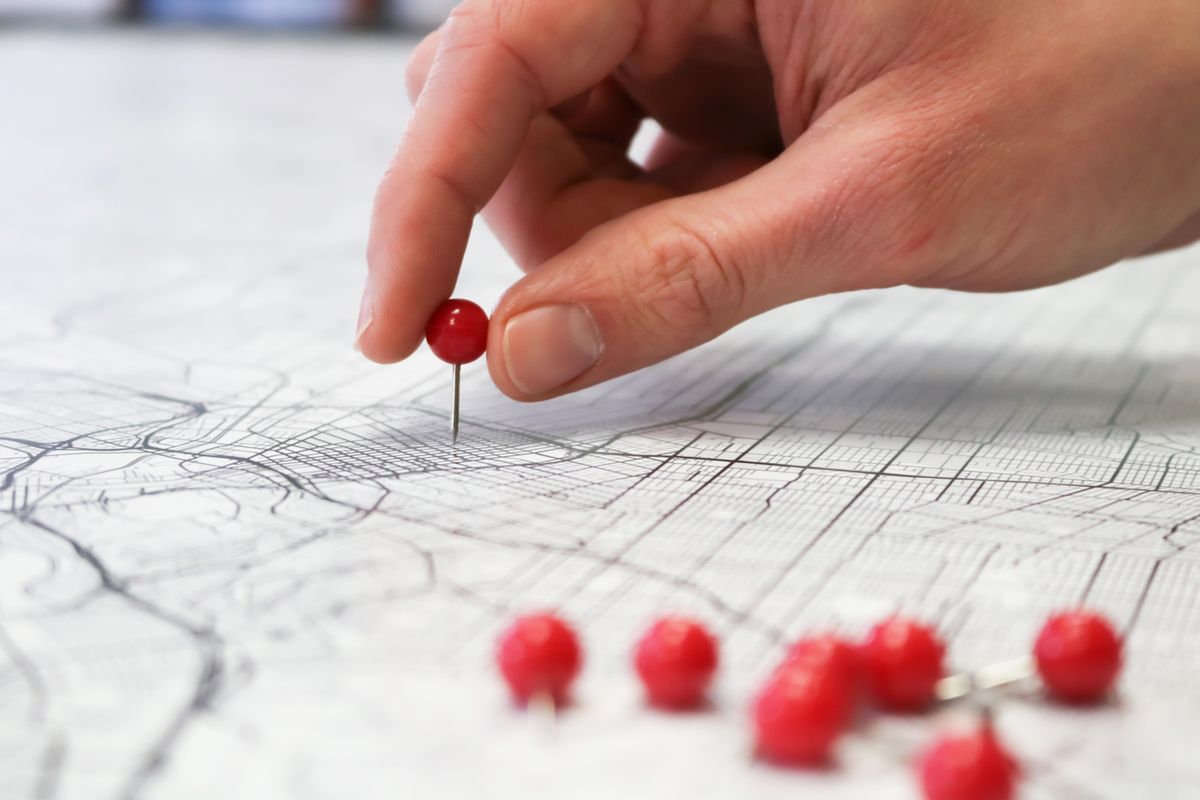 A hand placing a pin on a map, the way a medical practice sets its Google Ads targeting radius around the office