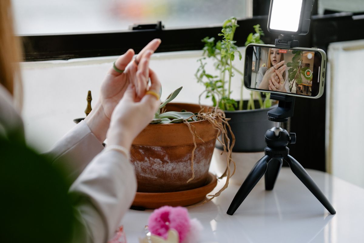 A person filming a short vertical video on a phone mounted on a tripod, the setup a medical practice uses to make social media clips