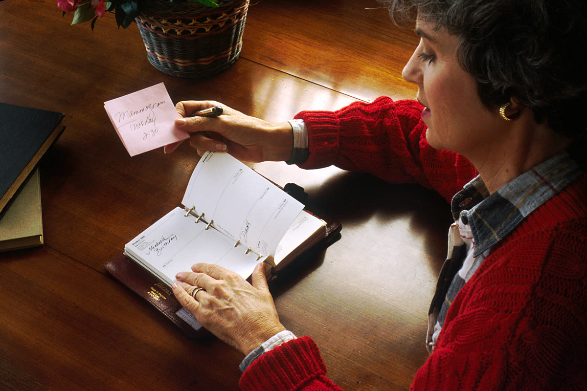 A person looking at an open appointment book, planning how many new patients a practice needs each month
