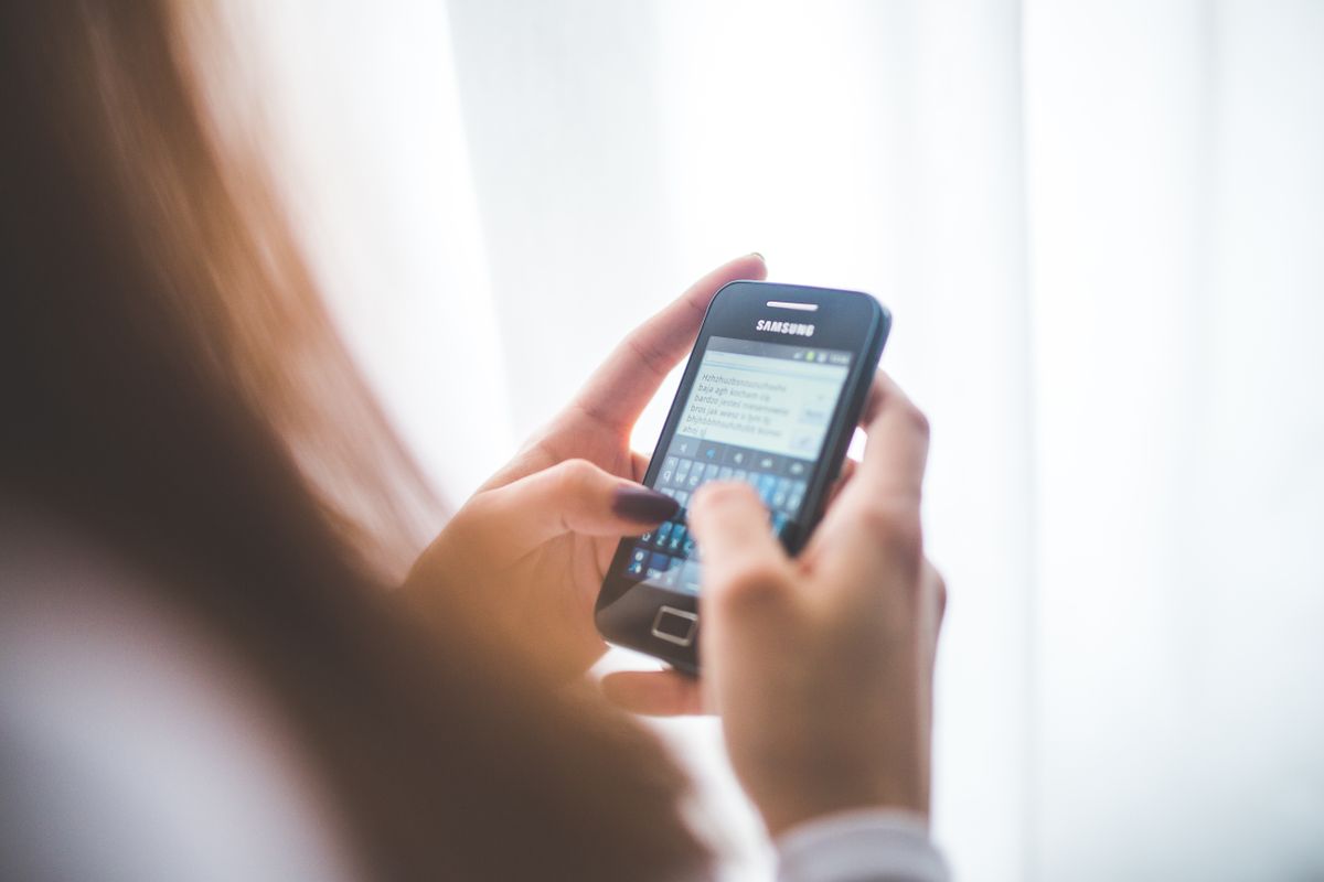 A person looking at a phone with a missed message, the way a patient lead waits for a practice to follow up