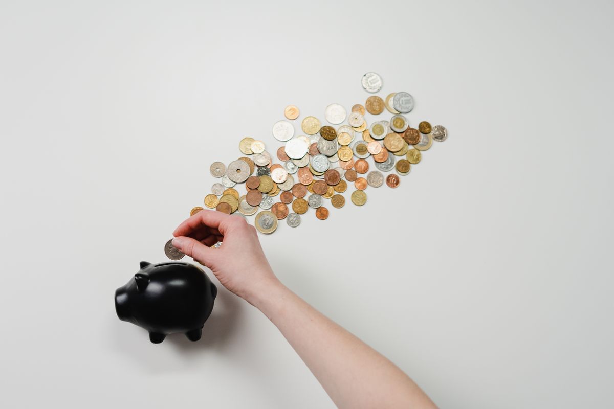 A hand dropping coins into a piggy bank, a simple picture of the cost to acquire a new patient for a medical practice