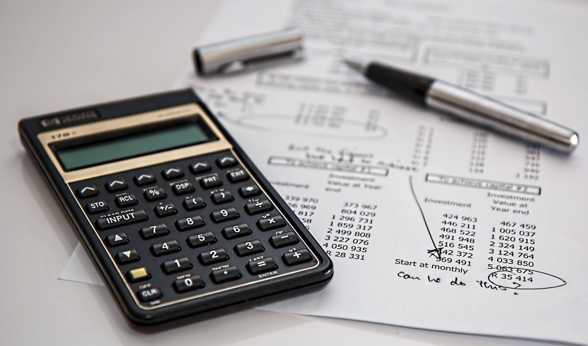 A calculator and financial paperwork on a desk, used to plan a medical practice marketing budget