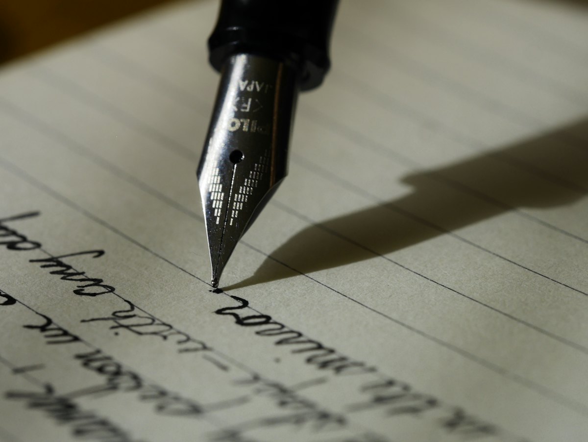A person writing in a notebook, planning how often a medical practice should publish blog posts