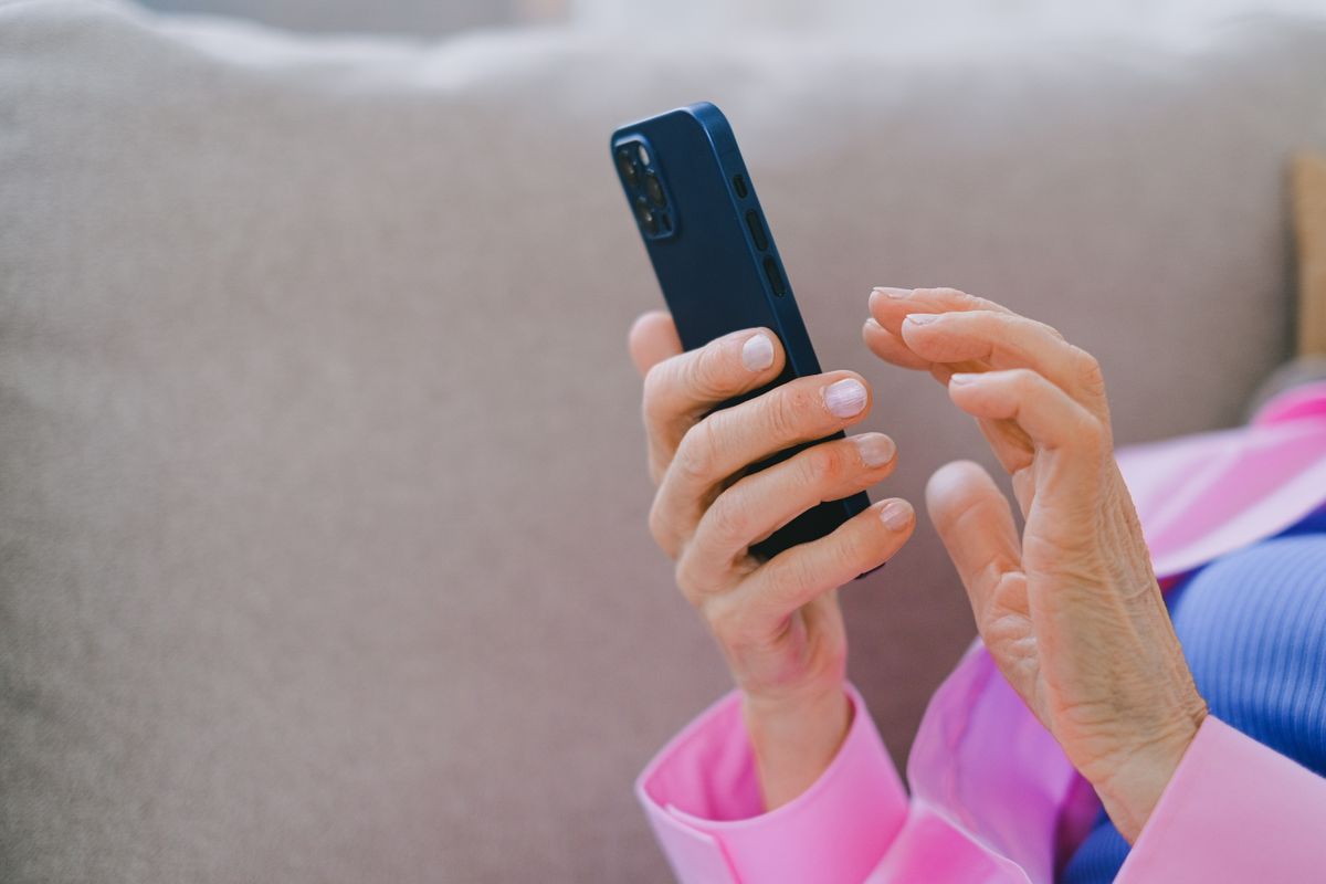 An older patient reading a review request text on a smartphone, the moment a good visit turns into a Google review