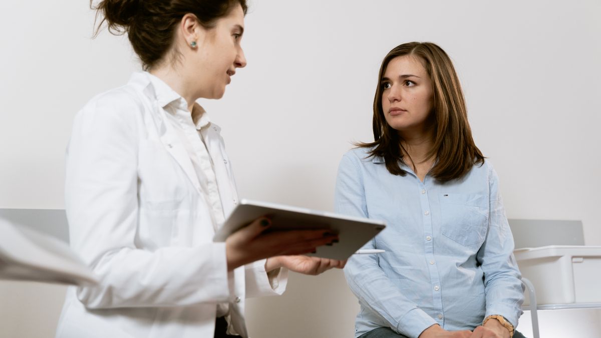 A doctor talking with a patient during a second opinion consultation, reviewing notes on a tablet while the patient listens closely
