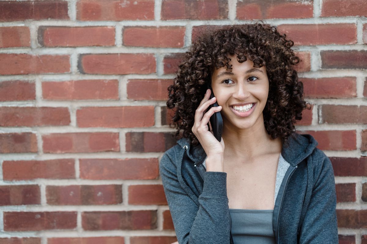 A young woman smiling on her smartphone, representing how millennial and Gen Z patients find and book medical care online