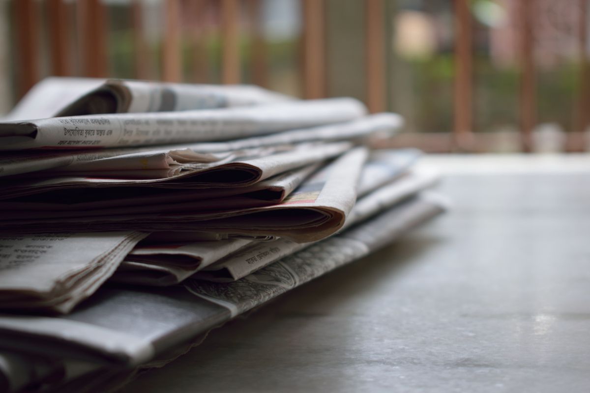 A stack of folded local newspapers on a table, representing earned local press coverage for a medical practice