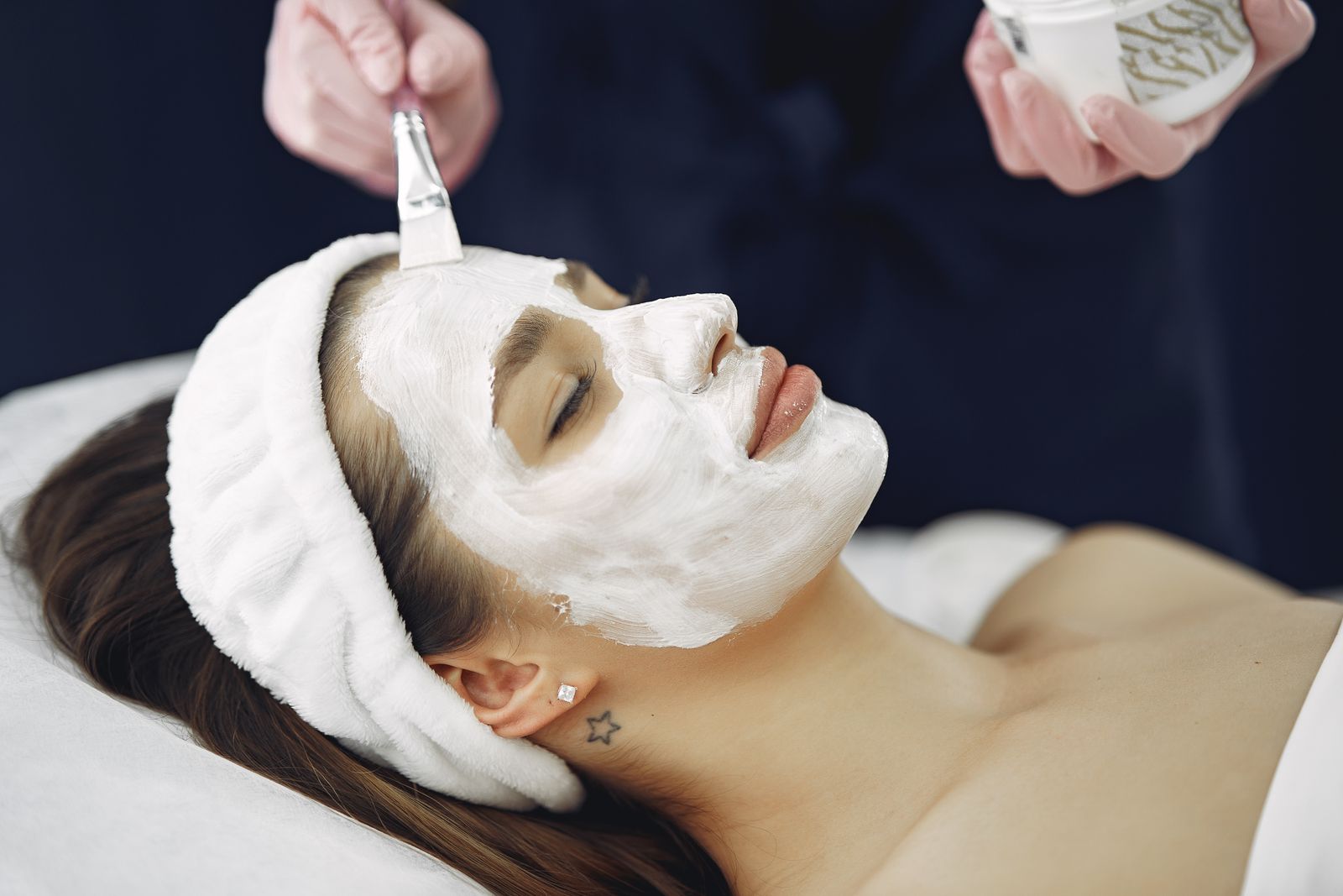 A patient relaxing during a facial aesthetic treatment at a Botox and injectables clinic while a gloved provider works