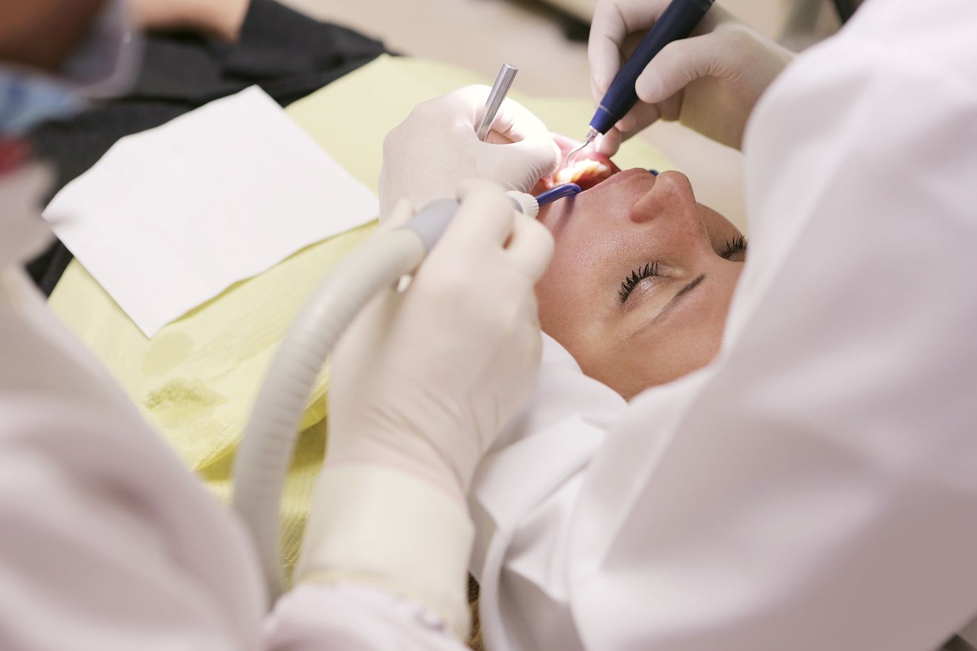 A dentist and assistant treating a patient in a modern dental office, representing dental practice care and patient trust