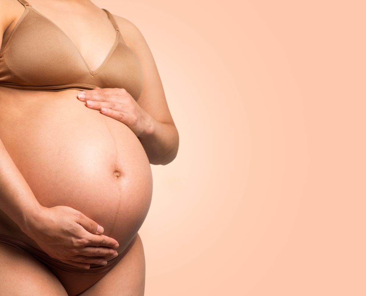 A pregnant belly held with both hands, the hopeful outcome every fertility clinic patient is working toward