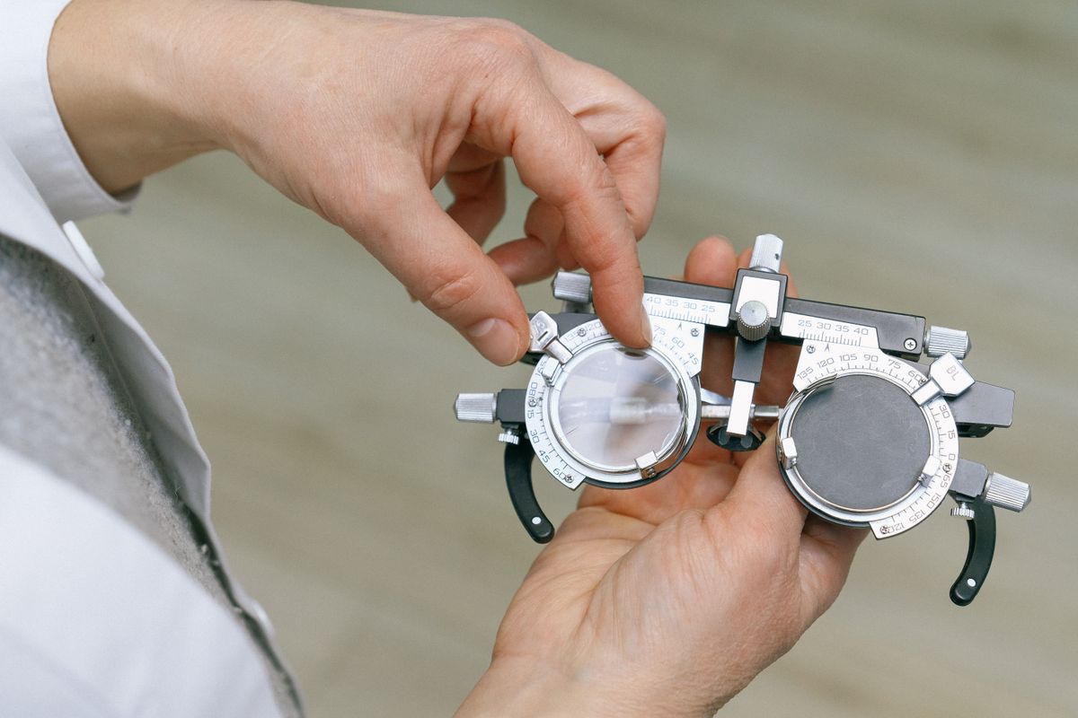 An eye doctor holding a trial frame during a vision exam, the kind of consultation a LASIK patient books after months of thinking about it