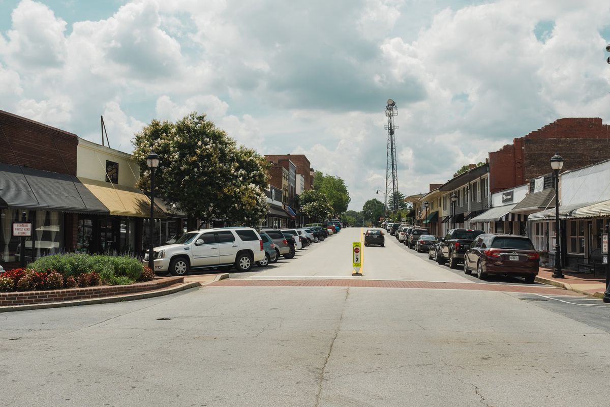 A calm American small town main street with storefronts and parked cars, the kind of tight community where a medical practice grows through local search and reputation