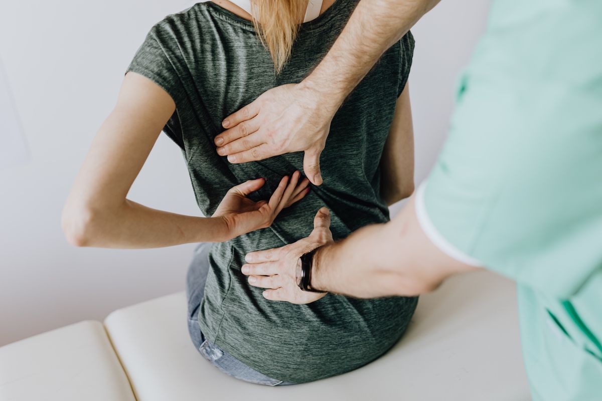 A pelvic floor physical therapist assessing a patient's lower back and pelvis during an evaluation