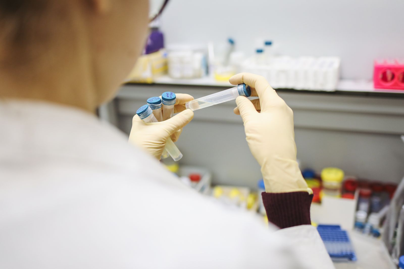 A provider in a white coat and gloves inspecting peptide vials at a wellness and peptide therapy clinic