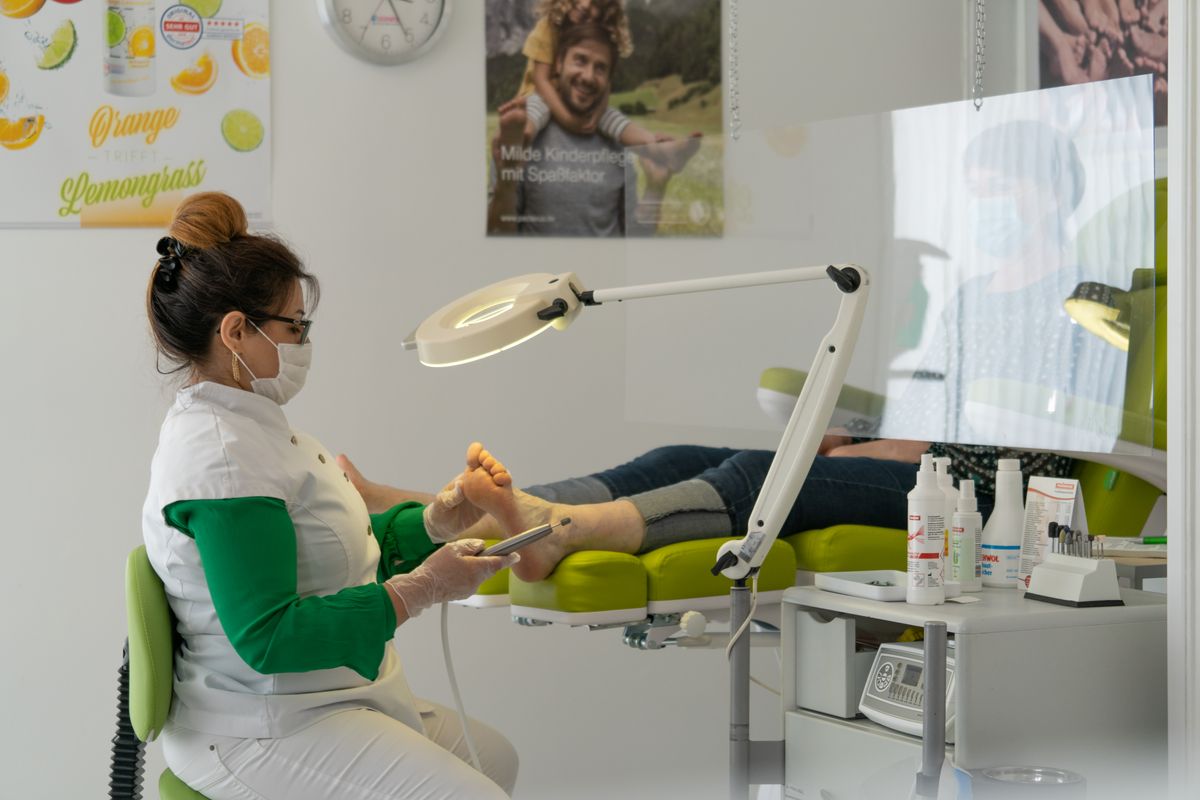 A podiatrist examining and treating a patient's foot in a clinic